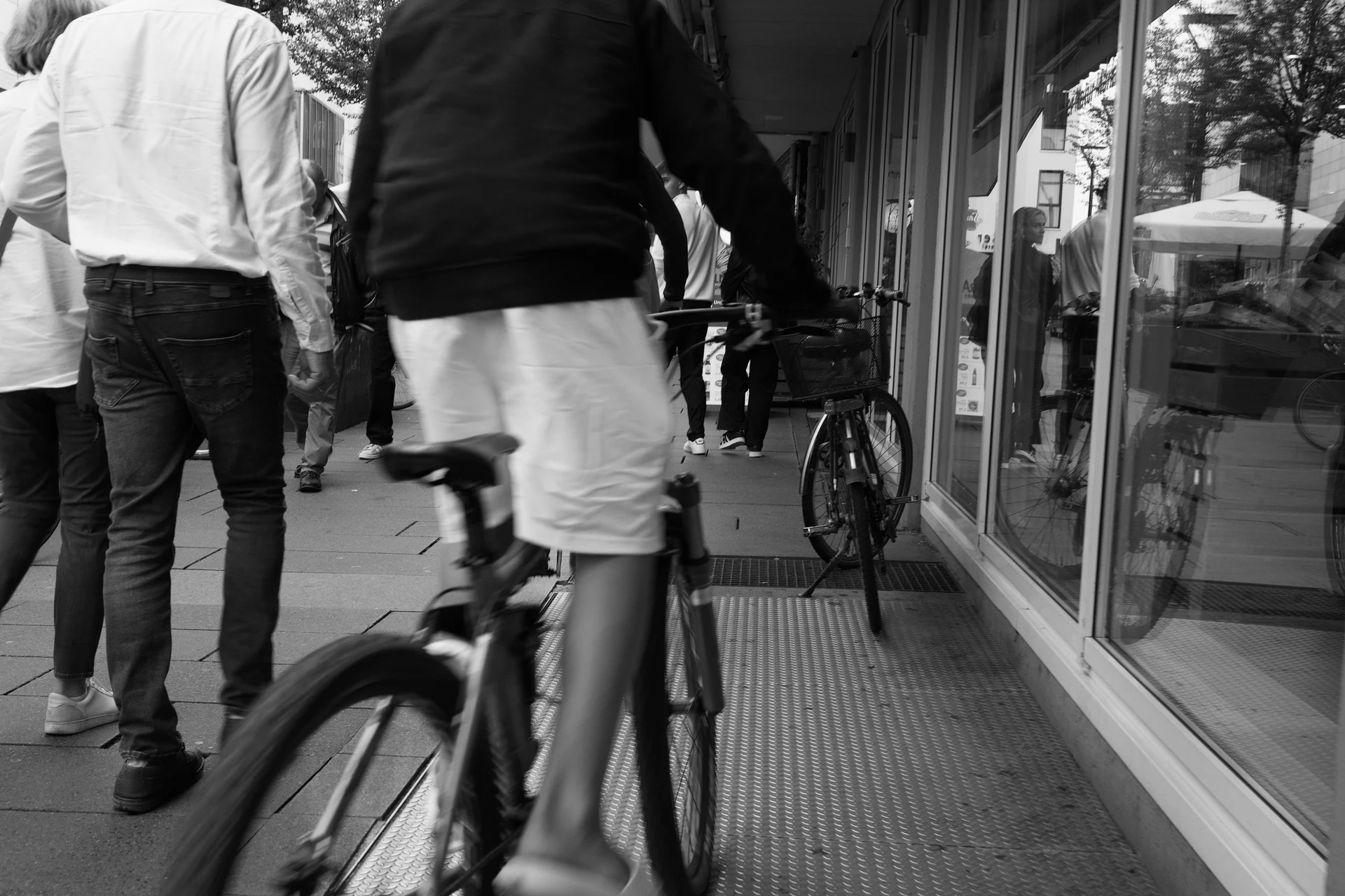 Busy urban scene with a person on a bicycle trying to get though many people on a pedestrian way.