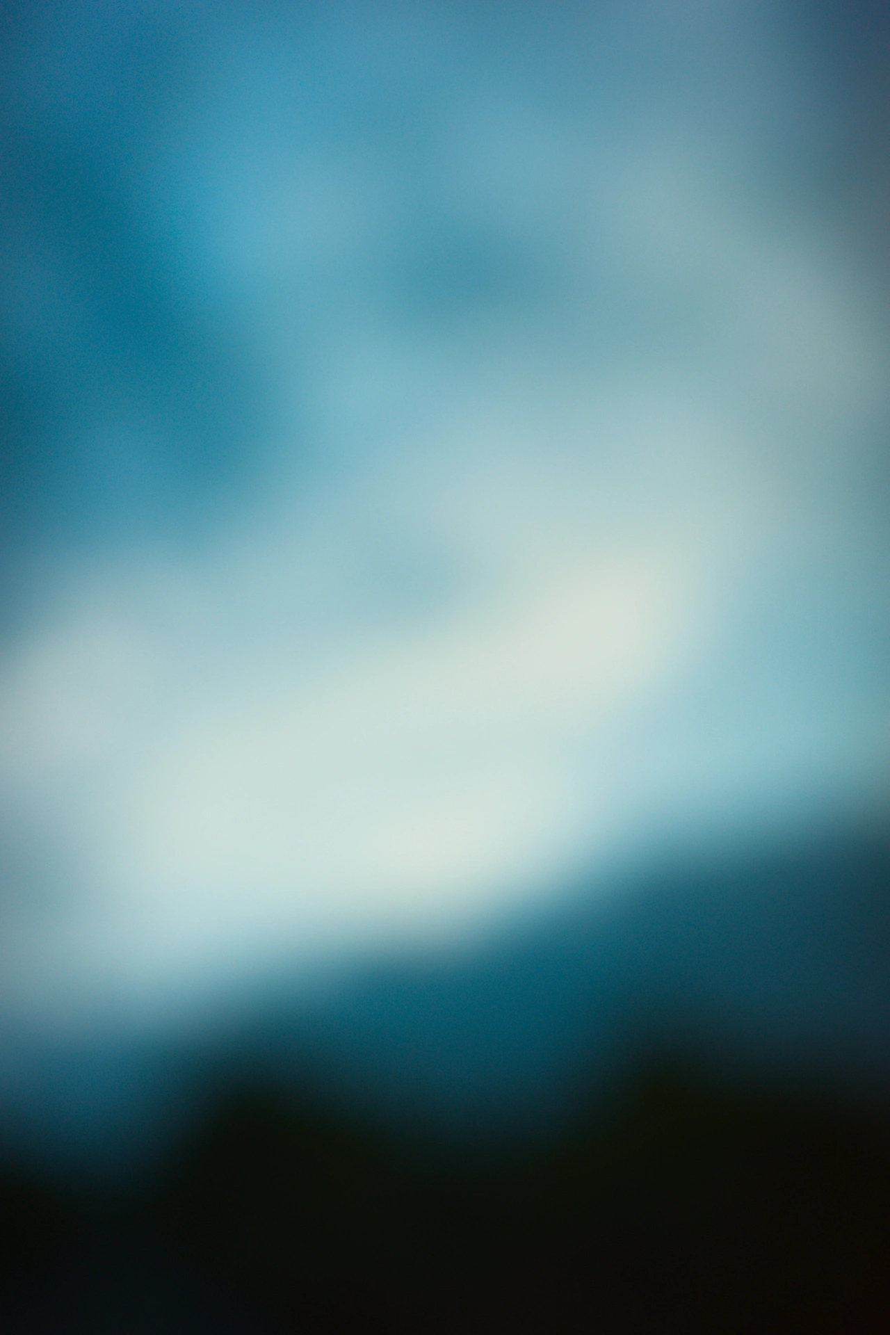 Abstract out-of-focus photo of a cloudy sky with the light coming though a bit more in the centre.